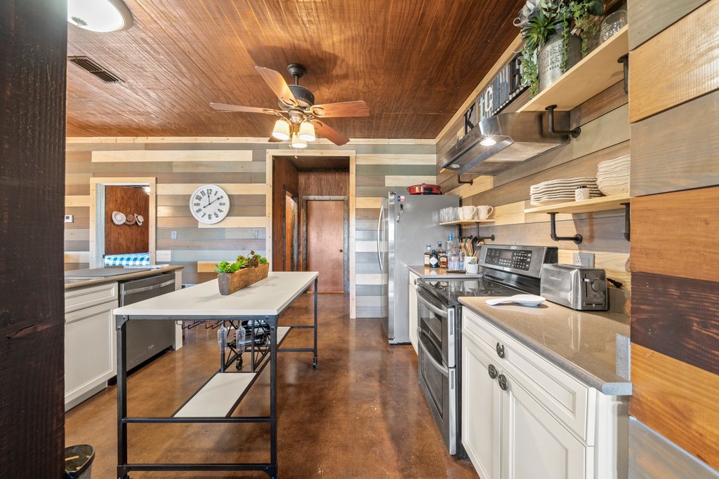 3259 Schumann Road Stonewall, TX 78671 - Photo 13 of 35 a kitchen with stainless steel appliances kitchen island granite countertop a sink a counter space and stainless steel appliances