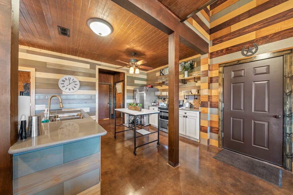 3259 Schumann Road Stonewall, TX 78671 - Photo 17 of 35 a dining hall with stainless steel appliances kitchen island granite countertop a refrigerator and cabinets