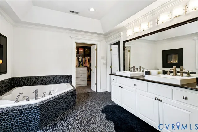 a bathroom with a bathtub a double vanity sink and a large mirror
