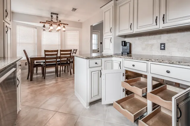 a kitchen with stainless steel appliances granite countertop a stove top oven a sink dishwasher and white cabinets