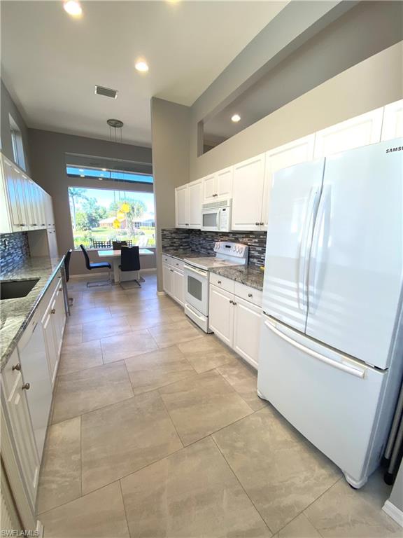 19307 Silver Oak Drive Estero, FL 33967 - Photo 11 of 43 a kitchen with stainless steel appliances granite countertop a stove a sink and a refrigerator