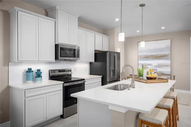 a kitchen with stainless steel appliances a sink a stove a refrigerator a center island and furniture