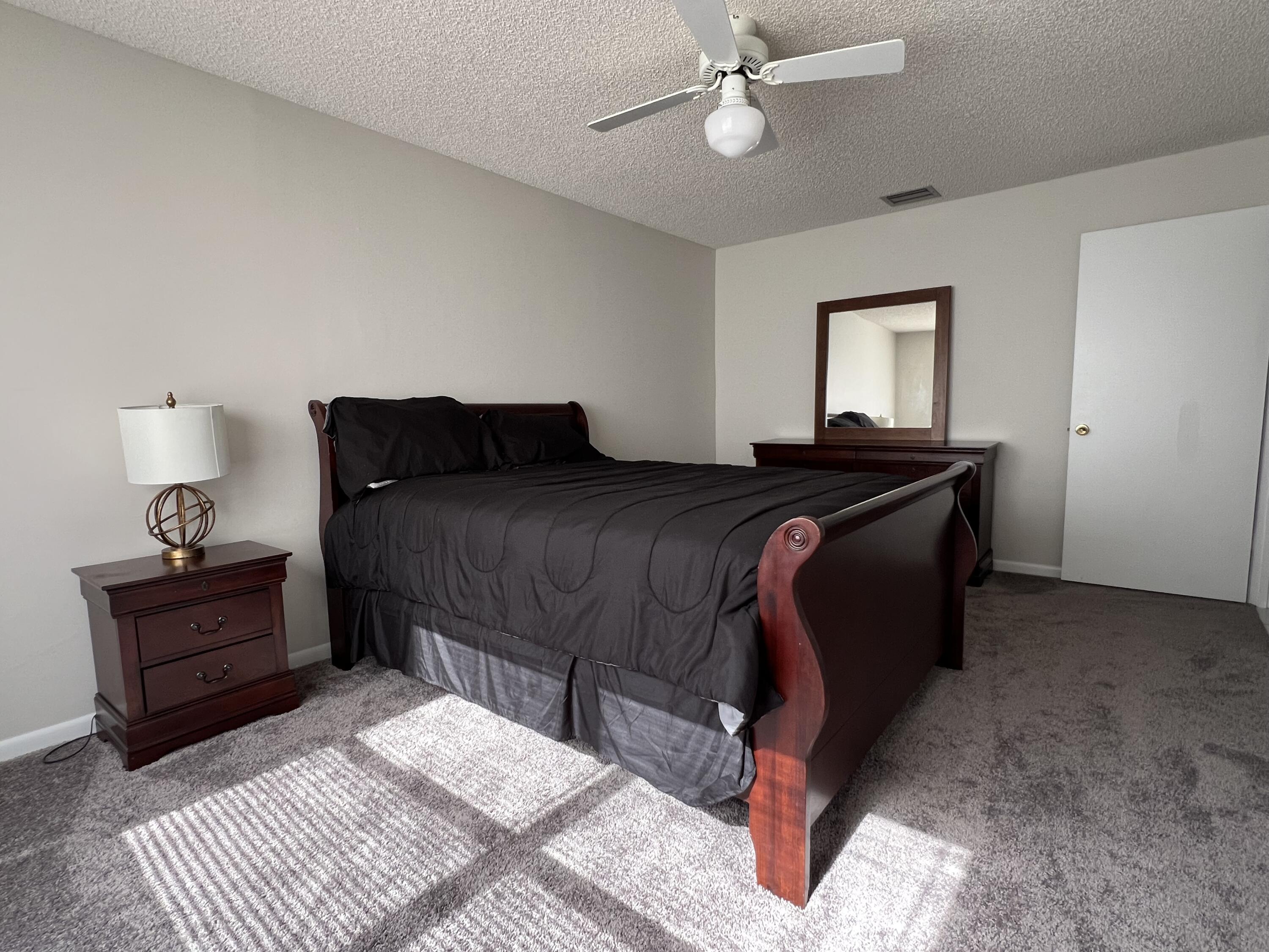 9775 Sun Pointe Drive Boynton Beach, FL 33437 - Photo 14 of 30 a bedroom with a bed and a chandelier