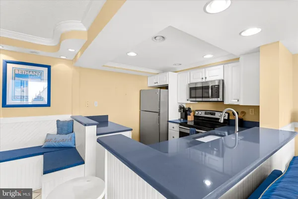 a kitchen with stainless steel appliances a refrigerator a stove a sink a dining table and chairs with wooden floor