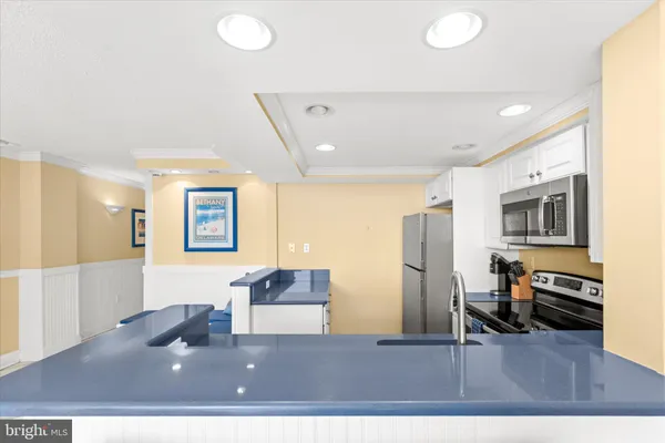 a living room with stainless steel appliances furniture a refrigerator and a counter top space
