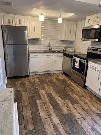 a kitchen with stainless steel appliances granite countertop a refrigerator a stove a sink and a microwave