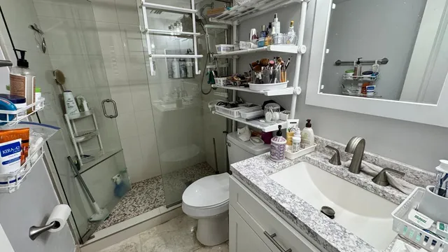 a bathroom with a granite countertop sink toilet and shower