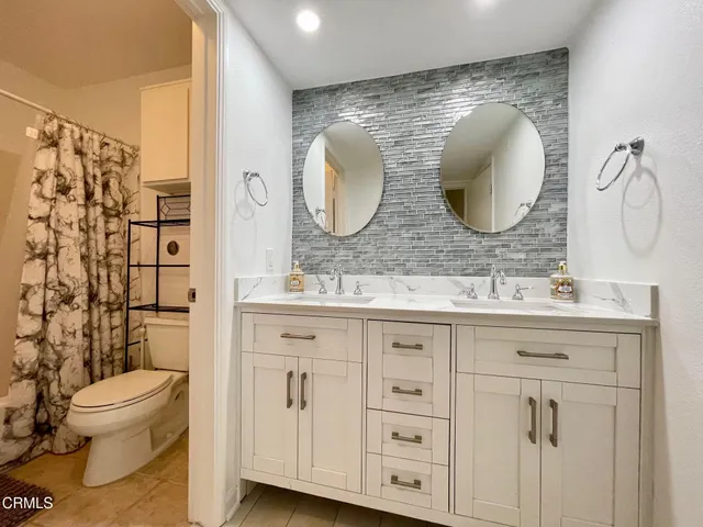 a bathroom with a double vanity sink mirror and toilet