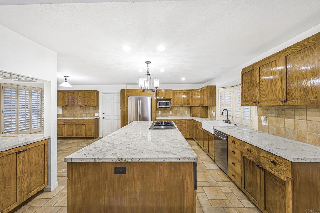 28720 Sandhurst Way Escondido, CA 92026 - Photo 29 of 57 a view of a kitchen with kitchen island a sink a counter top space and stainless steel appliances