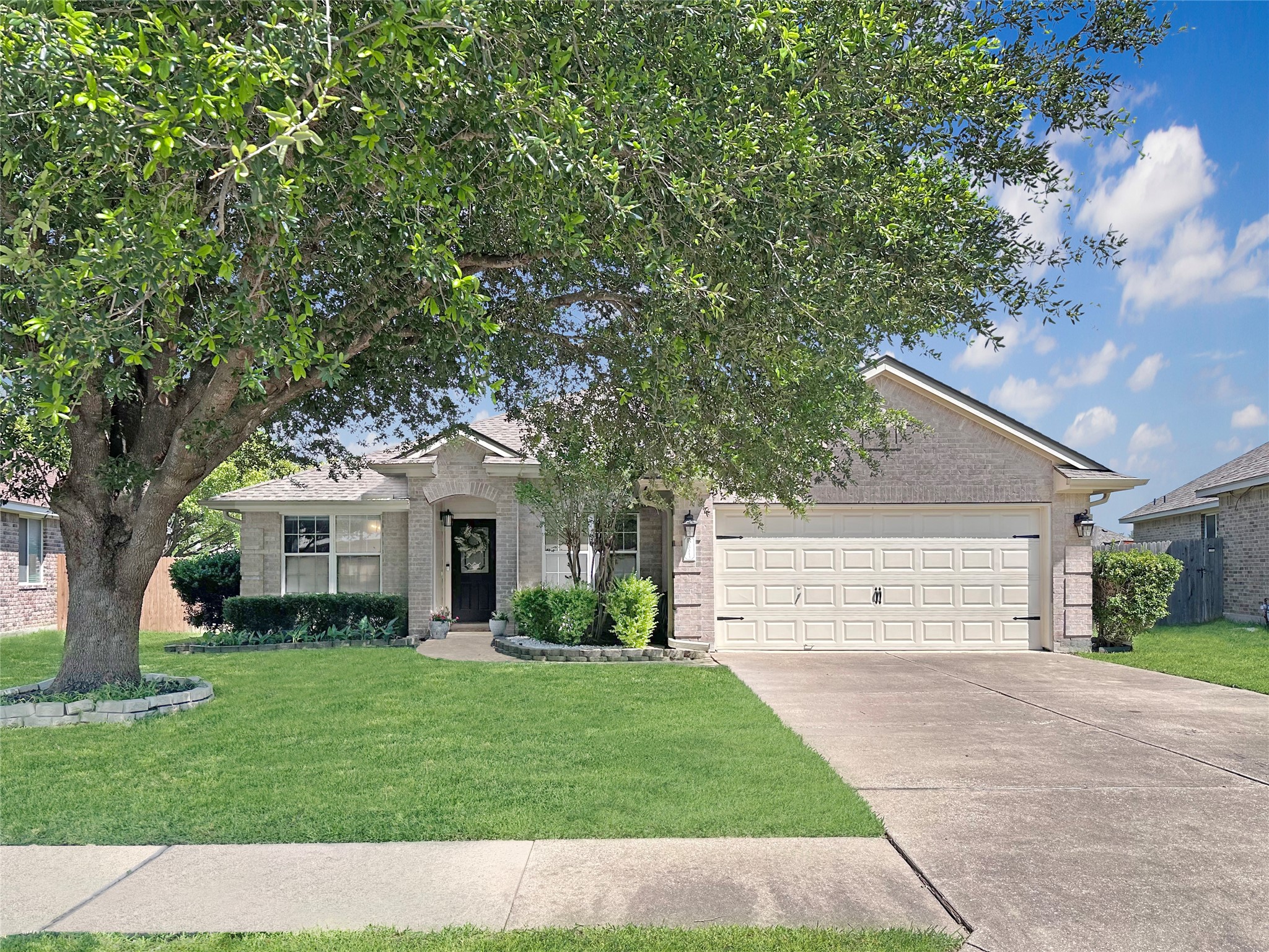 A welcoming facade, framed by mature trees, showcases this charming residence with an attached garage.