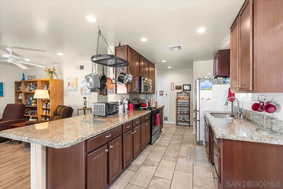 9254 Shadow Hill Road Santee, CA 92071 - Photo 15 of 34 a kitchen with stainless steel appliances kitchen island granite countertop a sink and cabinets