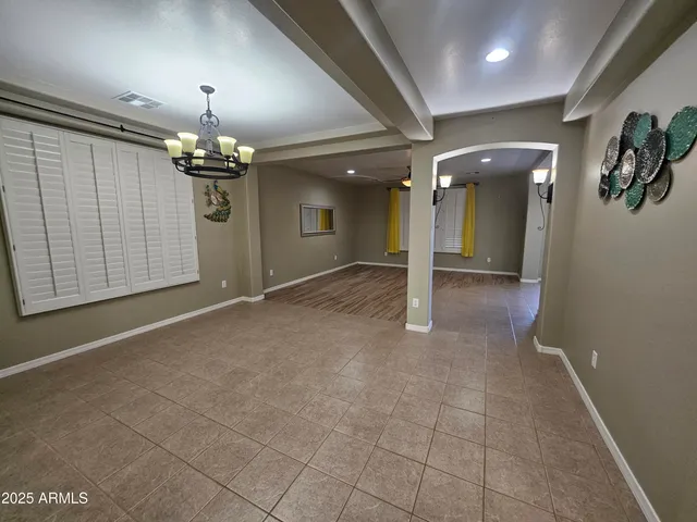 an empty room with kitchen view and natural light