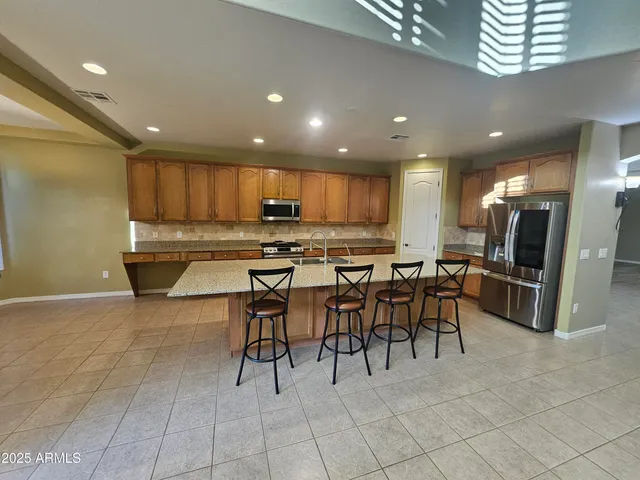 a kitchen with stainless steel appliances kitchen island granite countertop a refrigerator a stove a sink a dining table and chairs