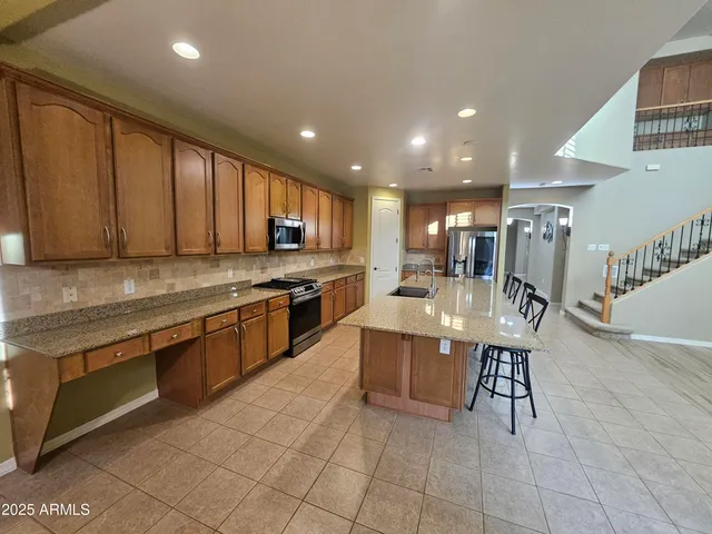 a large kitchen with stainless steel appliances granite countertop a stove a sink a oven with a dining table and chairs