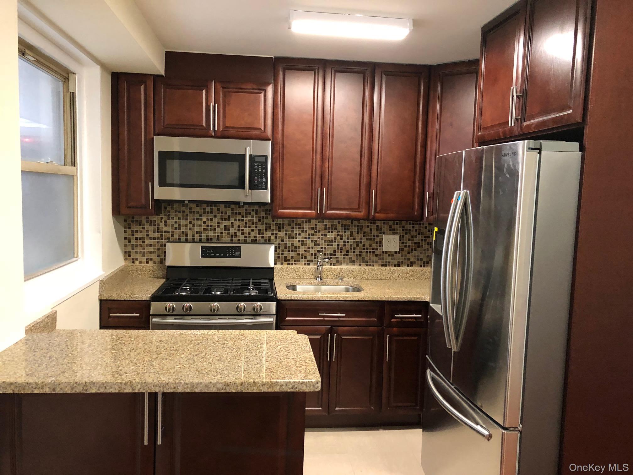 97-10 62nd Drive, Unit 9C Queens, NY 11374 - Photo 2 of 11 a kitchen with granite countertop a refrigerator stove and sink