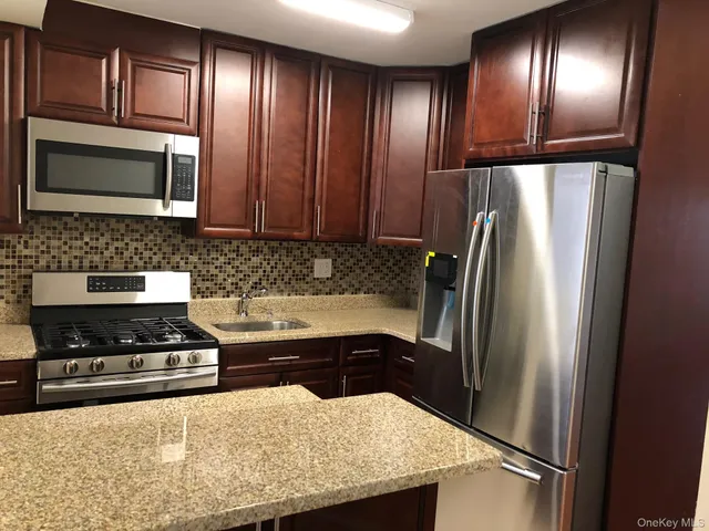 a kitchen with granite countertop stainless steel appliances and refrigerator