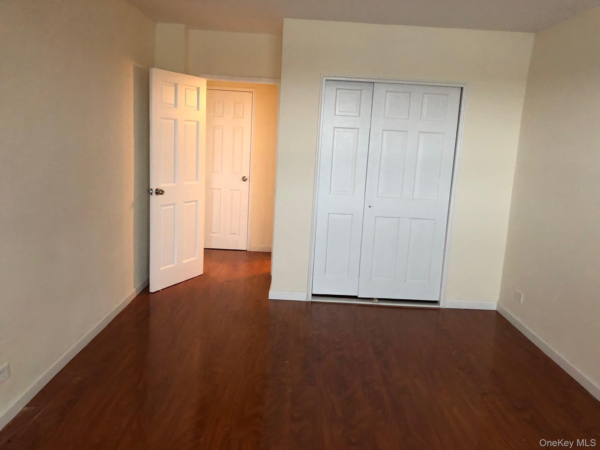 97-10 62nd Drive, Unit 9C Queens, NY 11374 - Photo 9 of 11 a view of an empty room with wooden floor