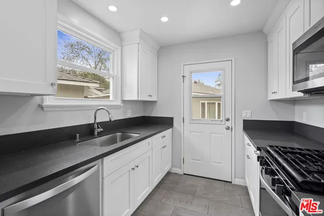 a kitchen with granite countertop a stove a sink and a microwave