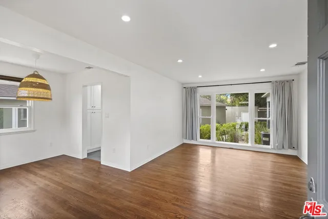a view of an empty room with wooden floor and window