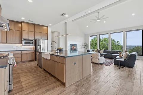 a large white kitchen with a large window a sink dishwasher and white cabinets with wooden floor