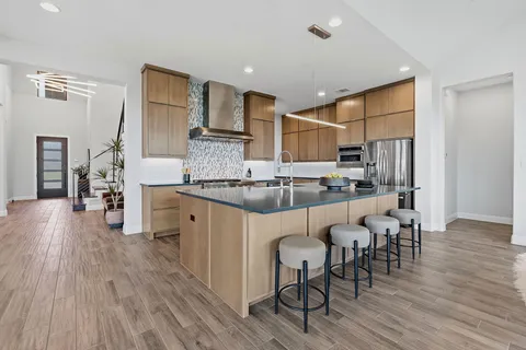 a kitchen with stainless steel appliances a dining table chairs and wooden floor