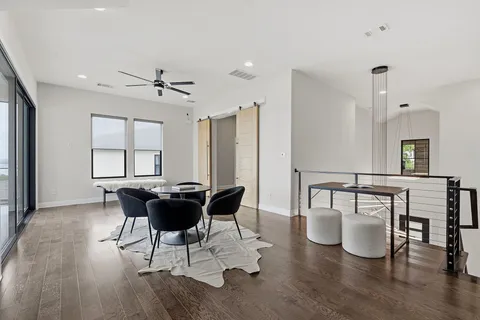 a dining room with wooden floor a chandelier a glass table and chairs