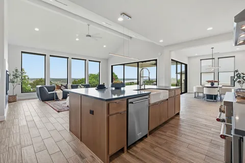 a large white kitchen with a large window and wooden floor