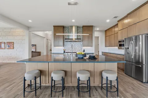 a kitchen with stainless steel appliances granite countertop a dining table chairs refrigerator and cabinets