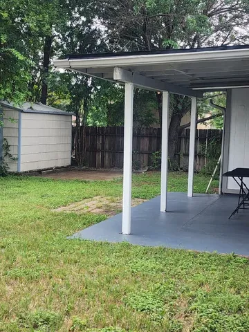a view of a backyard with large trees and wooden fence