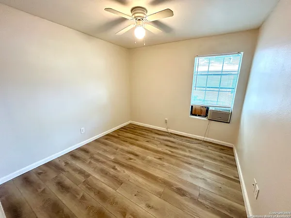 an empty room with windows and fan