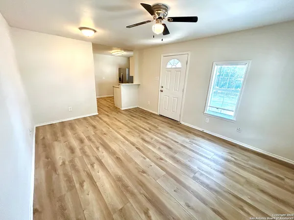 a view of empty room with wooden floor and fan