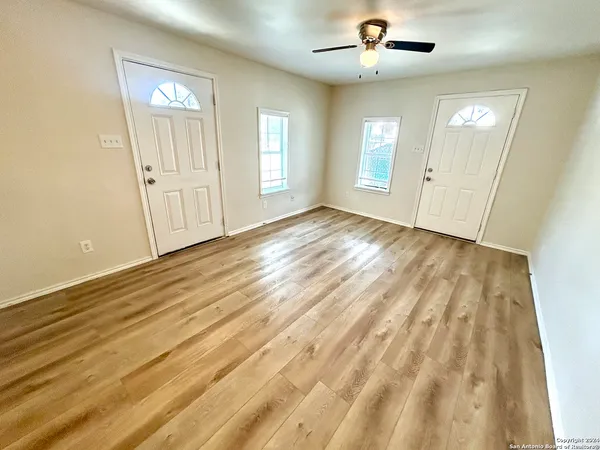 a view of an empty room with window and wooden floor
