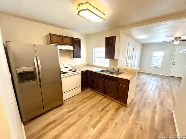 a kitchen with stainless steel appliances granite countertop a refrigerator a sink dishwasher a stove with wooden floor and cabinets