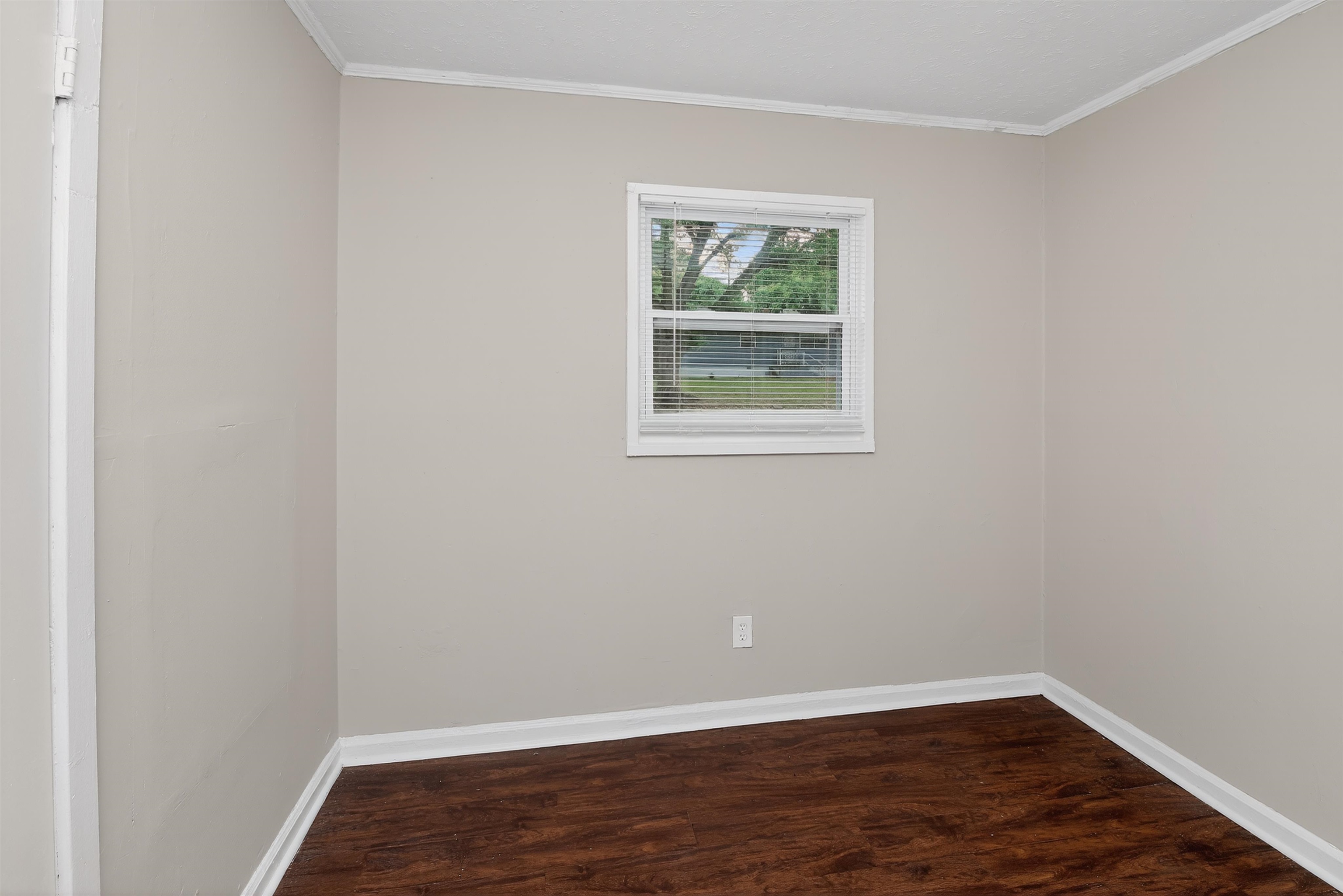 4838 Manson Road Memphis, TN 38109 - Photo 13 of 28 Neutral tone walls with white trim, wood-finish flooring, and a single window with blinds