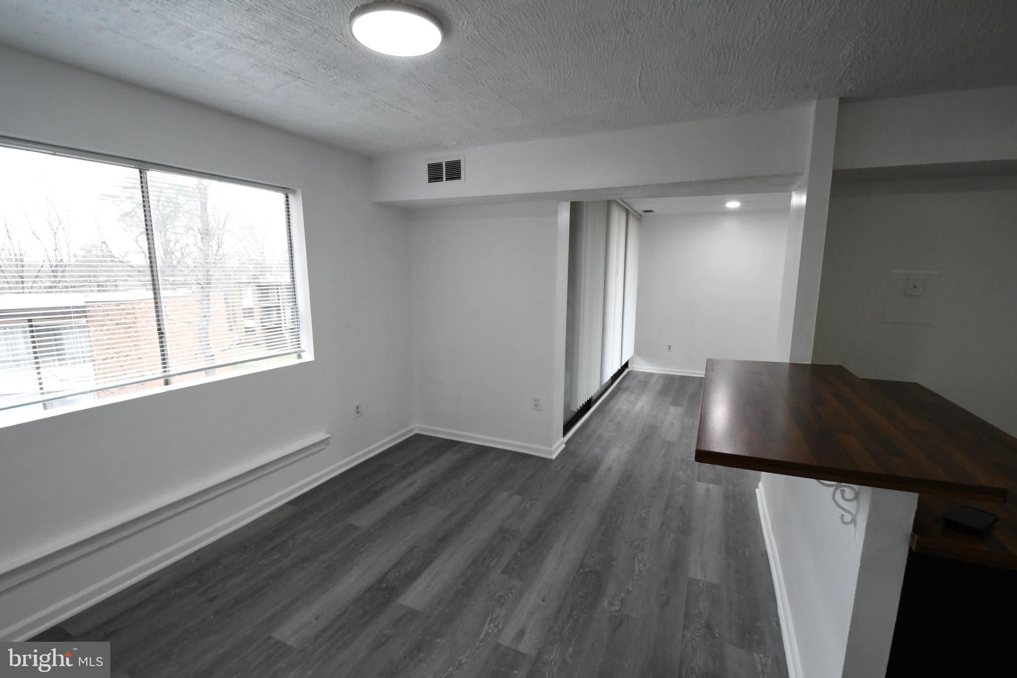 8459 Greenbelt Road, Unit 201 Greenbelt, MD 20770 - Photo 12 of 15 a view of an empty room with wooden floor and a window