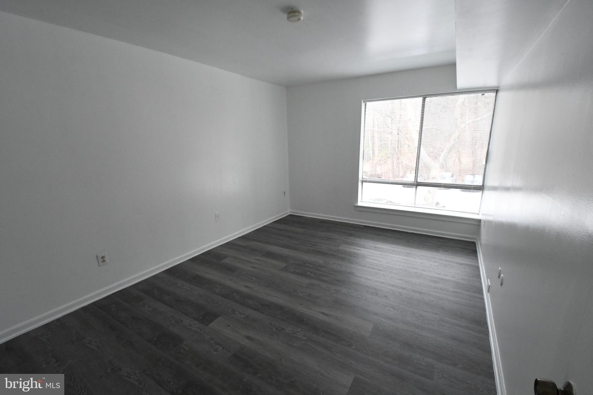 8459 Greenbelt Road, Unit 201 Greenbelt, MD 20770 - Photo 6 of 15 an empty room with wooden floor and windows