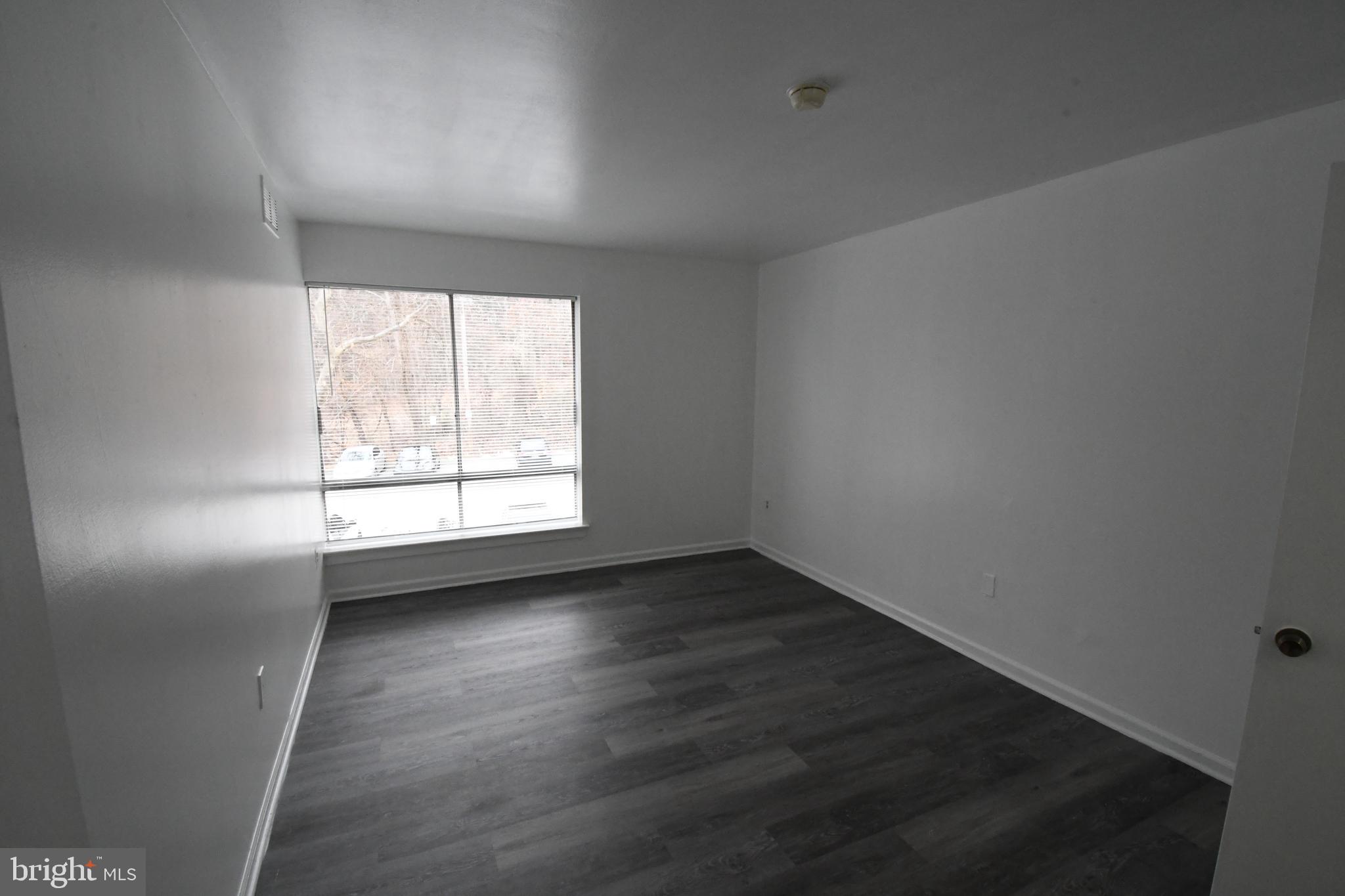 8459 Greenbelt Road, Unit 201 Greenbelt, MD 20770 - Photo 8 of 15 an empty room with wooden floor and windows