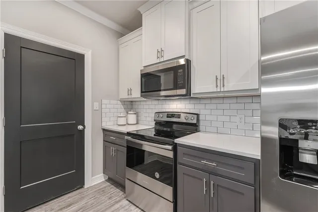 a kitchen with cabinets stainless steel appliances and wooden floor
