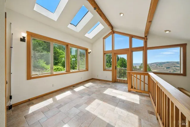 a view of an empty room with wooden floor and windows