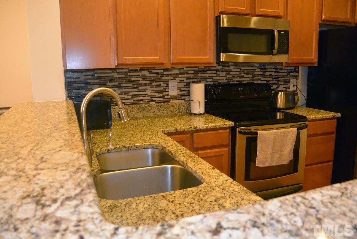1029 Summerhouse Road Cary, NC 27519 - Photo 5 of 17 a view of a kitchen counter top space a sink and a stove with wooden floor