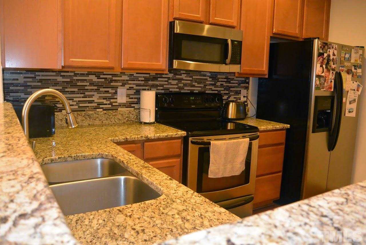 1029 Summerhouse Road Cary, NC 27519 - Photo 7 of 17 a kitchen with stainless steel appliances granite countertop a sink stove and refrigerator
