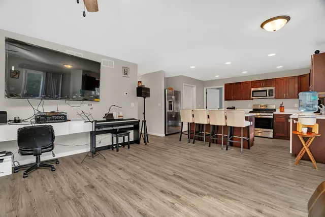 a living room with stainless steel appliances furniture and a wooden floor