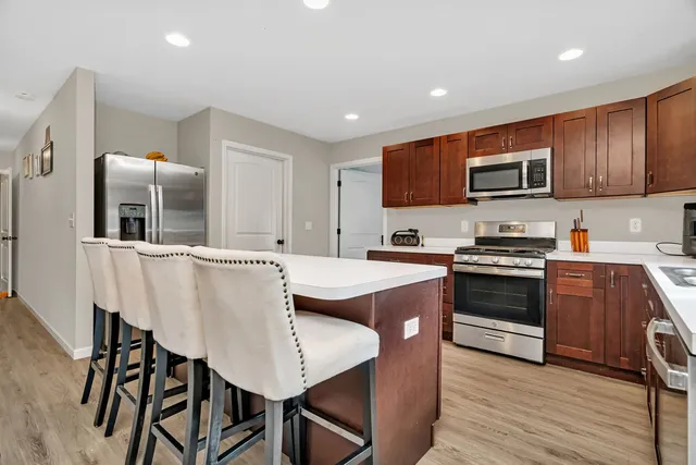 a kitchen with stainless steel appliances granite countertop a stove a sink dishwasher a microwave oven and a refrigerator with wooden cabinets