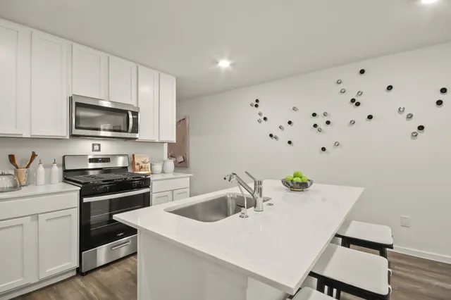 a kitchen with granite countertop a sink dishwasher stove and microwave with wooden floor