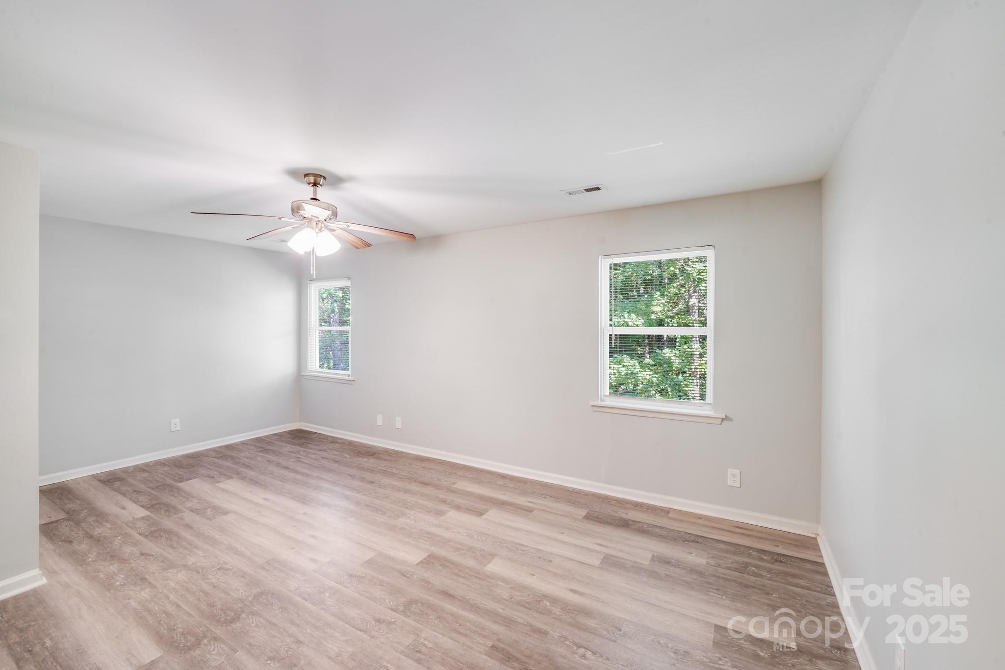 6226 Spanish Oak Road Charlotte, NC 28227 - Photo 19 of 28 an empty room with a chandelier fan and windows