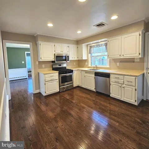 a large kitchen with stainless steel appliances a large counter top and a stove top oven