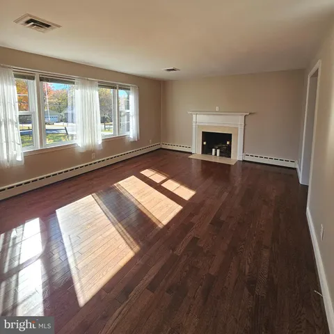 a view of a livingroom with wooden floor and a fireplace