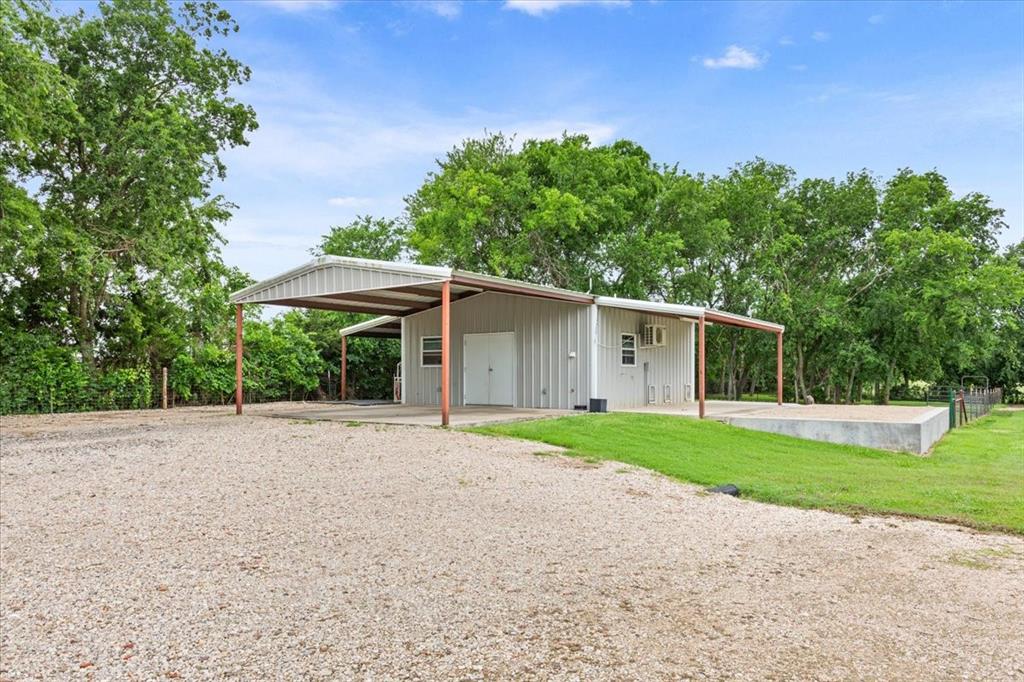 259 County Road 149 Riesel, TX 76682 - Photo 36 of 40 View of front of property featuring a front yard, an outdoor structure, view of wooded area, and a garage