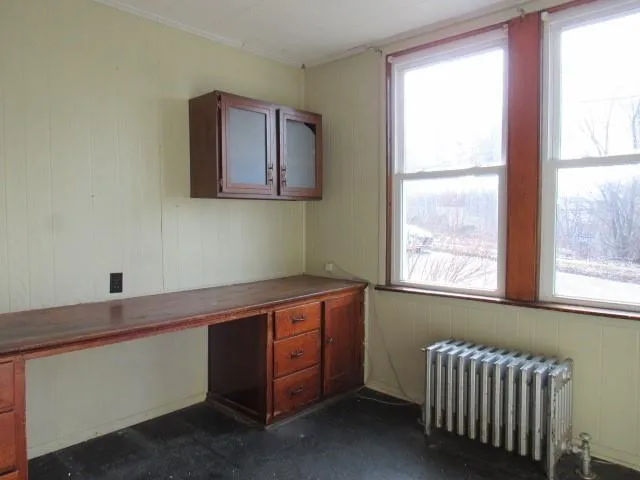 a view of an empty room with wooden floor and stairs