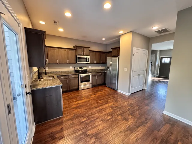 a kitchen with stainless steel appliances granite countertop a refrigerator and a stove top oven